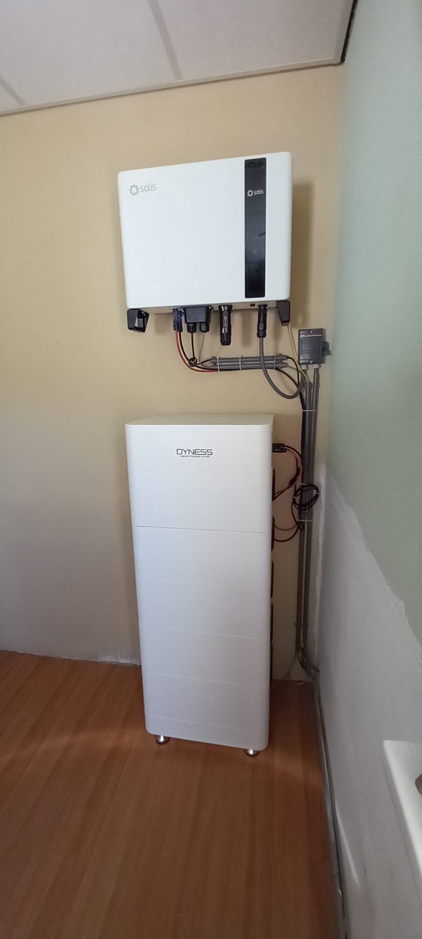 Solis omvormer en Dyness thuisbatterij tegen een gele wand